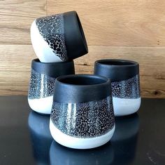 three black and white vases sitting on top of a table