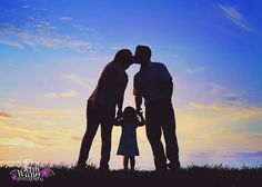 two adults and a child standing in front of a sunset