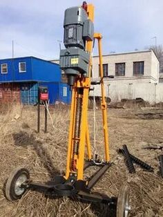 a machine that is sitting in the middle of some grass and dirt with buildings in the background