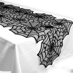 a black lace table runner on top of a white tablecloth with spider webs