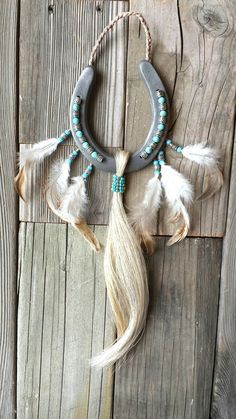 a necklace with feathers and beads hanging on a wooden wall