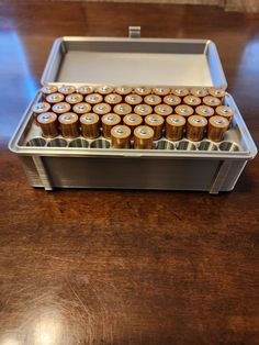 an aluminum container filled with lots of batteries on top of a wooden table