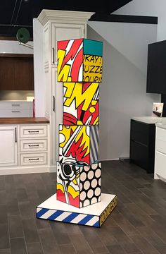 a tall colorful object sitting on top of a kitchen floor next to a white cabinet