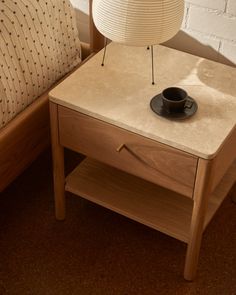 a table with a lamp on it next to a bed