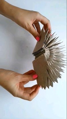 two hands are holding small pieces of paper with spikes on them and one hand is reaching for it