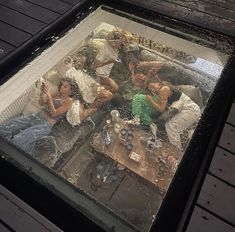 the reflection of people sitting on couches in a glass table with water splashing over them