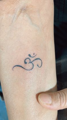 a person with a small tattoo on their left arm and the word om written in cursive writing