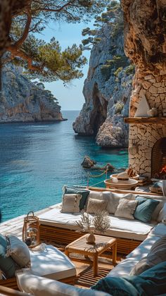 an outdoor seating area overlooking the ocean and rocky cliffs, with blue water in the background