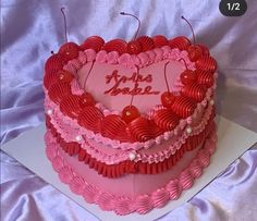 a heart shaped cake with pink icing and red decorations