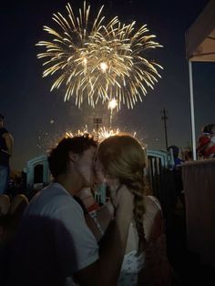 a man and woman kissing in front of fireworks