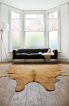 a living room filled with furniture and a large rug on top of a hard wood floor