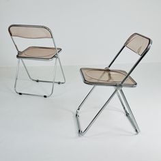 two folding chairs sitting side by side on a white surface, one with a beige seat and the other without