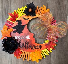 a welcome halloween wreath made out of popsicle sticks and pumpkins on a wooden floor