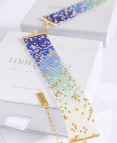 a blue and white bracelet sitting on top of a box next to a gold chain