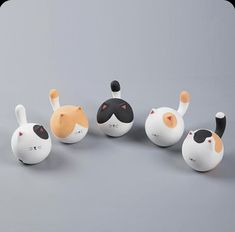 five ceramic cats and one dog sitting in a circle on a gray surface with grey background