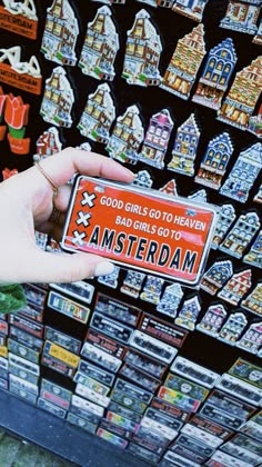 a person holding up a small sticker in front of a store display filled with magnets