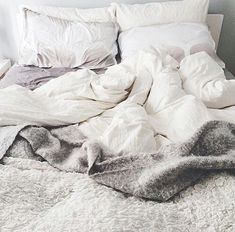 an unmade bed with blankets and pillows