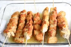 chicken skewers are being cooked in a glass dish