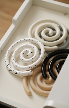 an assortment of different colored rings in a white box on a wooden table with wood flooring