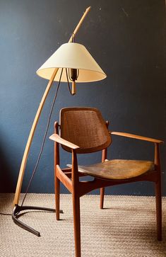 a wooden chair sitting next to a lamp on top of a carpeted floor in front of a blue wall