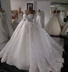 a white wedding dress on display in a room with mannequins and dresses