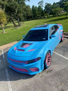 a blue car with pink rims parked in a parking lot