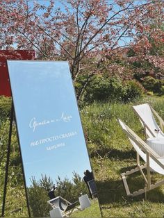 a large mirror sitting on top of a grass covered field next to a white lawn chair