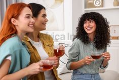 three women sitting on a couch drinking tea and laughing at each other's company