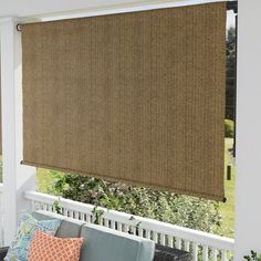 a couch sitting on top of a porch next to a window covered in brown blinds