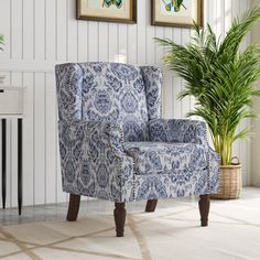 a blue and white chair sitting next to a potted plant in a living room