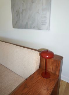 a red lamp sitting on top of a wooden table next to a white couch in a living room