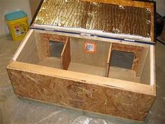 an open wooden box sitting on top of a piece of plywood with gold foil covering it