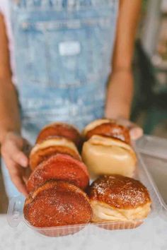 a person holding some doughnuts in a plastic container