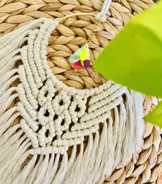 a close up of a woven piece of cloth with a plant in the corner next to it