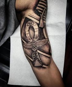 a man's arm with an egyptian cross and an eagle tattoo on the arm