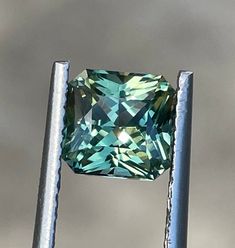 a fancy green diamond sitting on top of a metal pole in front of a cloudy sky