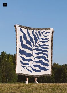 a woman standing in front of a blue and white blanket with a leaf design on it