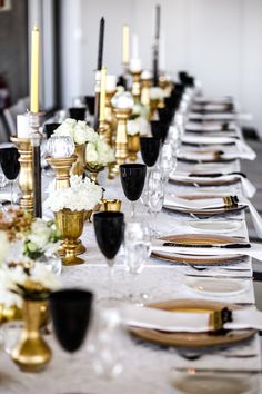 a long table is set with black and gold place settings