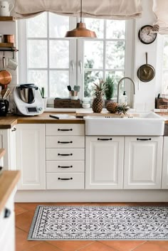 a kitchen filled with lots of white cabinets and counter top space next to a window