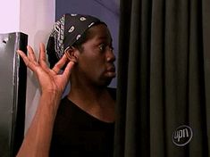 a man wearing a bandana talking on his cell phone in front of a refrigerator