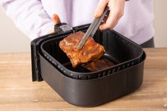 a person cutting meat in a black container