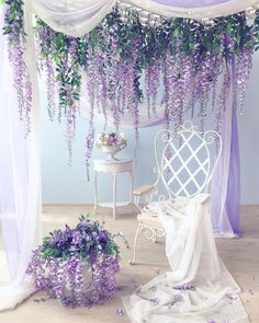 purple flowers are hanging from the ceiling in a room with white furniture and drapes