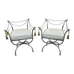 a pair of wrought iron chairs with white cushions