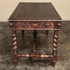 an old wooden table with ornate carvings on the top and legs, sitting on concrete