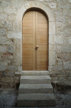 an arched wooden door with steps leading up to it