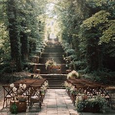 an outdoor ceremony setup with wooden chairs and floral centerpieces on the steps leading up to the wedding venue