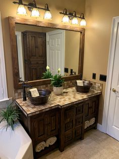 a bathroom with two sinks and a large mirror above the sink is lit by three lights