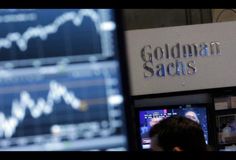 a man standing in front of a computer monitor with the words goldman sacks on it