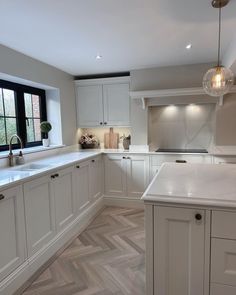 a large kitchen with white cabinets and wood flooring on the walls, along with an island in the middle