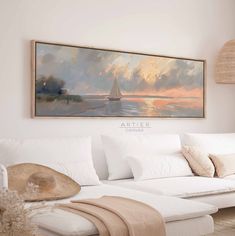 a painting hanging on the wall above a couch in a room with white furniture and pillows